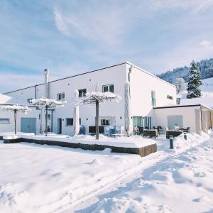 Ein weißes Gebäude im Schnee mit Bäumen darin. in der Unterkunft Pension fein & sein in Schwarzsee