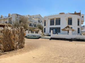 a group of white buildings with straw at Das Haus am Meer in Safaga