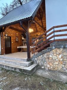 a wooden cabin with a porch and a staircase at Kuća za odmor Ema in Gospić