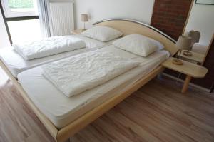 ein großes Bett mit weißer Bettwäsche und Kissen darauf in der Unterkunft Kustverhuur Park Schoneveld Zeester 66 in Breskens
