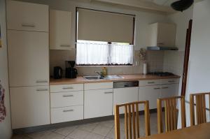 eine Küche mit weißen Schränken, einem Waschbecken und einem Fenster in der Unterkunft Kustverhuur Park Schoneveld Zeester 66 in Breskens