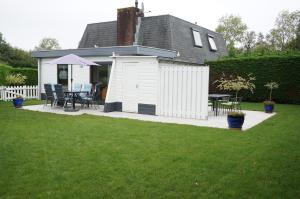 a white shed with a table and chairs in a yard at Kustverhuur Park Schoneveld Zeester 66 in Breskens