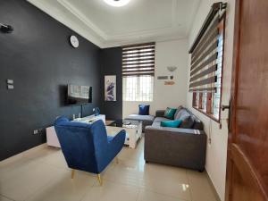 uma sala de estar com uma cadeira azul e um sofá em Mawolè em Cotonou