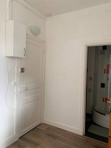Dieses weiße Zimmer verfügt über eine Tür und einen Spiegel. in der Unterkunft JO 2024 Studio proche gare (RER A, lignes J et L) in Sartrouville