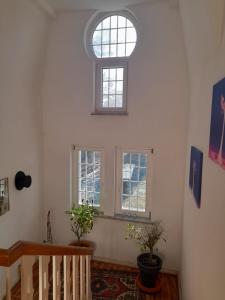 a room with three windows and a staircase with potted plants at Kurpension Parkfrieden in Bad Pyrmont