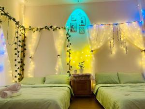 - une chambre avec 2 lits avec des lumières et une planche de surf sur le mur dans l'établissement House Thị Đà Lạt, à Đà Lạt