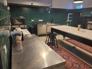 una cocina con encimera de acero inoxidable y azulejos verdes en Boutique hotel MEŅĢELES PIENOTAVA en Meņģele
