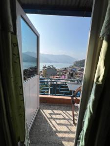 a room with a balcony with a view of the water at Little Pilgrim Family Lodge in Pokhara
