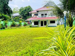 a white house with a red roof and a green yard at Abode Homestay Alleppey Near Omanapuzha Beach in Alleppey