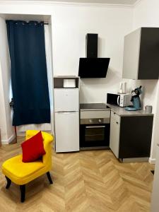 a small kitchen with a yellow chair and a table at Appartement T2 avec terrasse proche cathédrale in Bourges
