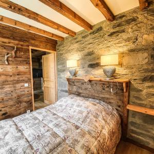 a bedroom with a bed and a stone wall at LA DENT PARRACHEE in Termignon