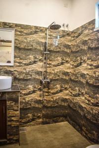 uma casa de banho com um chuveiro e uma parede de pedra em Lawrence Villa em Weligama