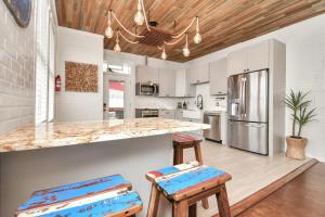 una cocina con armarios blancos y una barra con taburetes en Nautical Loft with Outdoor Kitchen & Beach Access en Galveston