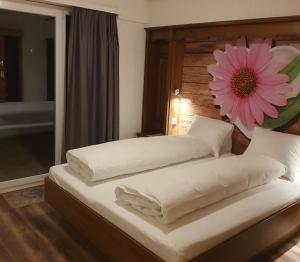 a bedroom with two beds with a pink flower on the headboard at Hotel dala in Leukerbad