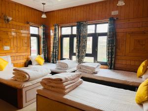 Whostels Srinagar في سريناغار: غرفه فيها اربع اسره شبابيك