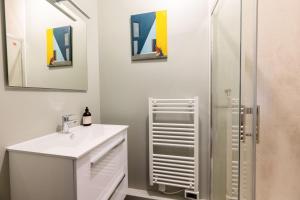 La salle de bains blanche est pourvue d'un lavabo et d'une douche. dans l'établissement Le Central - Au coeur de Bourges, à Bourges