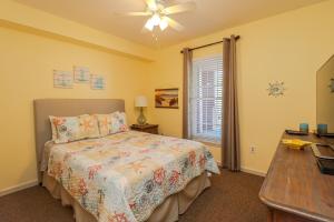 a bedroom with a bed with a ceiling fan and a desk at Seaside at Anastasia C203 in St. Augustine