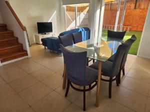 comedor con mesa de cristal y sillas en Casa Puertas del mar, en La Serena