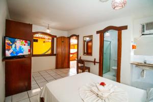 um quarto com uma cama, uma televisão e uma casa de banho em Village Arraial BY MN Hoteis em Arraial d'Ajuda
