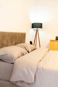Una cama con sábanas blancas y una lámpara. en Chrigrey Holiday Apartments & Durres Beach, en Durrës