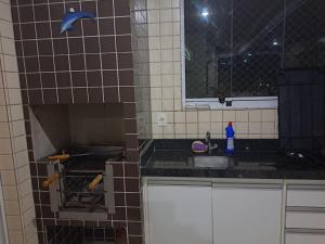 a kitchen with a sink and a tile wall at Apartamento Praia Grande SP in Praia Grande