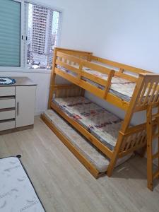 a bunk bed in a room with a desk at Apartamento Praia Grande SP in Praia Grande