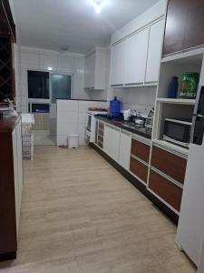 a kitchen with white cabinets and a wooden floor at Apartamento Praia Grande SP in Praia Grande