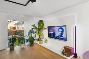 a living room with potted plants and a tv on the wall at Day Young Life/DYLHosting 130qm Pool/Garten/Parkpl in Nürnberg