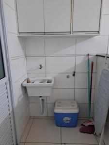 a small bathroom with a sink and a trash can at Apartamento Praia Grande SP in Praia Grande