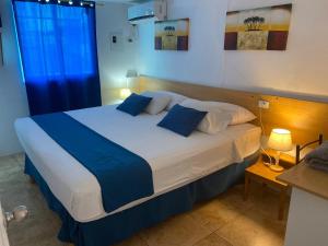 1 dormitorio con 1 cama grande con almohadas azules y blancas en Hostal Casa Latina en Manta