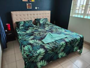 a bedroom with a bed with a green leafy bedspread at Mawolè in Cotonou