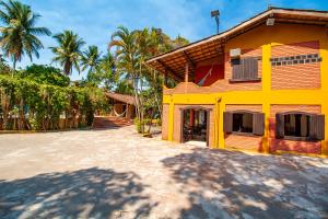 Una casa amarilla y roja con palmeras detrás. en Village Arraial BY MN Hoteis, en Arraial d'Ajuda