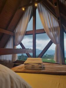 een slaapkamer met een groot raam met witte gordijnen bij Cabana na montanha, com hidro e vista espetacular. 