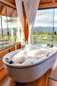 een bad in een kamer met een raam bij Cabana na montanha, com hidro e vista espetacular. 