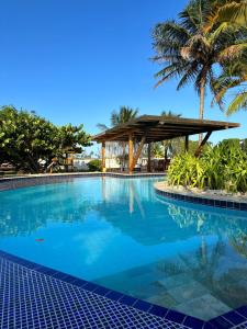 a swimming pool with a palm tree and a pavilion at Ecco Village - Serrambi in Porto De Galinhas