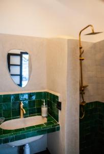 ein grün gefliestes Bad mit einem Waschbecken und einem Spiegel in der Unterkunft Cosy Riad in Marrakesch