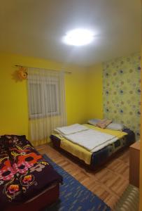 a bedroom with two beds in a room with yellow walls at APARTMAN ČAROLIJA TREBINJE in Trebinje