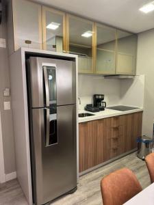 a kitchen with a stainless steel refrigerator and wooden cabinets at Infinity Tower Flat - 1403 in Itapema