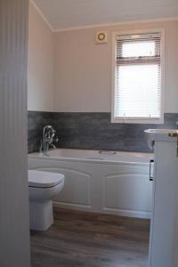 a bathroom with a tub and a toilet and a window at Luxury 3 bedroom lodge with free in lodge wifi in Carnforth
