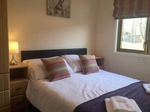 a bedroom with a white bed with pillows and a window at Luxury 3 bedroom lodge with free in lodge wifi in Carnforth