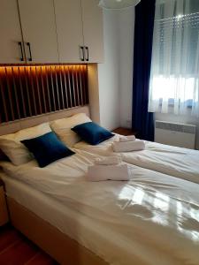 a large white bed with two blue pillows on it at Apartman Felicita 2 in Zlatibor