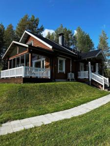 a house with a porch and a lawn in front of it at Villa Ihanus 100 m2 ja rantasauna järven rannalla in Kuusamo
