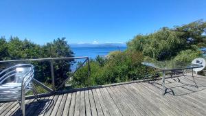a deck with a table and chairs and a view of the water at Cabañas tunquelen in Osorno