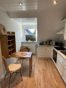 a kitchen with white cabinets and a table and a window at Ferienwohnung Fehn in Rhauderfehn