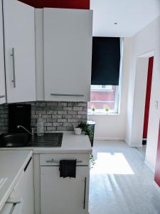 uma cozinha com armários brancos e uma parede de tijolos em Close to Liège Guillemens em Liège