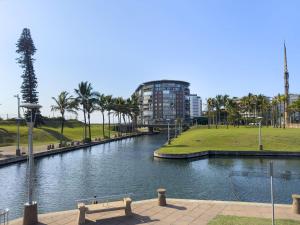 a river with a bench and a building in the background at Beach Haven Townhouse in Durban