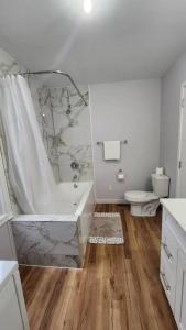 a white bathroom with a tub and a toilet at St B. Living in Winnipeg