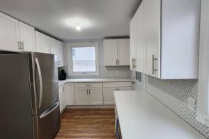 cocina con armarios blancos y nevera de acero inoxidable en St B. Living, en Winnipeg