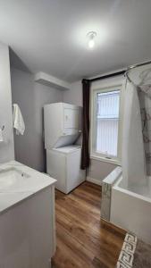 La salle de bains blanche est pourvue d'un lavabo et d'une fenêtre. dans l'établissement St B. Living, à Winnipeg
