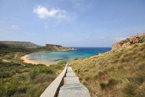 zwei Menschen gehen einen Weg zum Strand entlang in der Unterkunft Seaside Serenity - A lovely apartment with views in Mellieħa